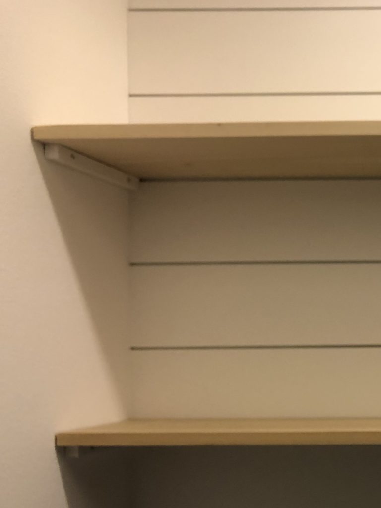 Shelf hack. Showing a closeup of how we secured the shelves between two walls using 1x1 wood pieces.